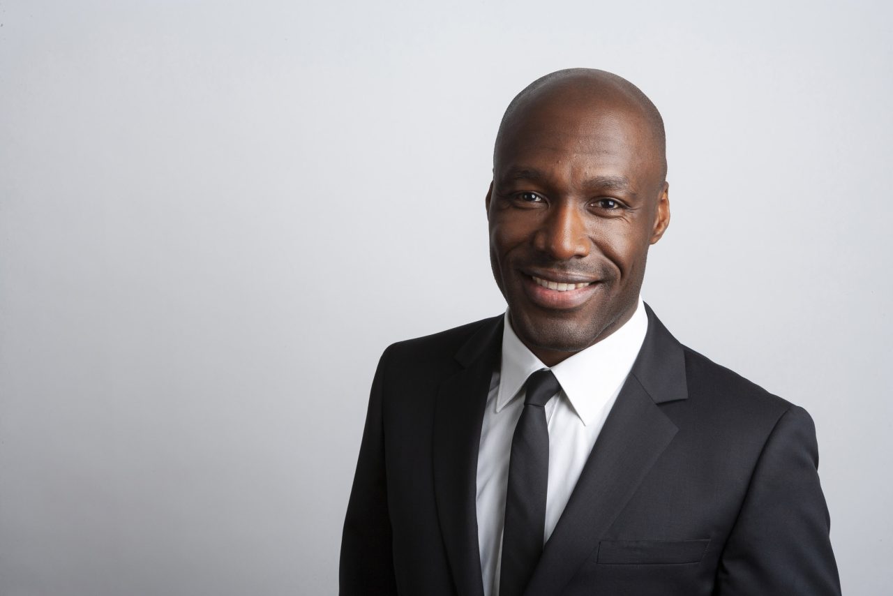 Portrait corporate classique en couleur d'un homme souriant en veste et cravate sur fond gris clair, portait réalisé en studio